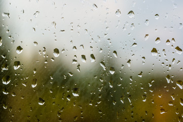 raindrops on window glass on background of cloudy sky