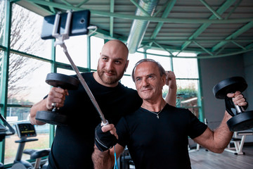 two friends athletes takes a selfie while lifting dumbbells