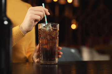 Wall Mural - Woman with glass of refreshing cola at table indoors, closeup. Space for text