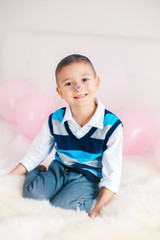 Wall Mural - Portrait of funny white Caucasian cute adorable smiling child boy with purple heart sticker on his nose. Valentine day holiday concept.