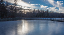Sunset Over Trees Around Frozen Lake In Winter