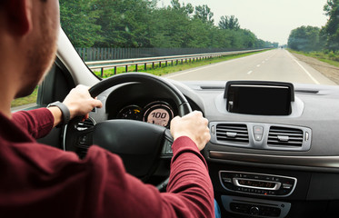 The young man driving the modern car on asphalt road