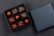 Assortment of luxury bonbons with red splashes in box on black background