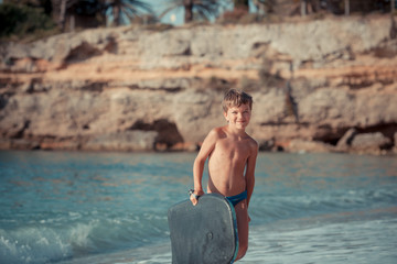 Portrait of happy cute boy swimming in sea, surf board, outdoor