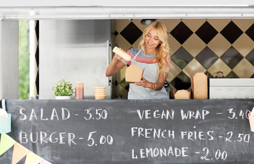 Poster - street sale and people concept - happy young saleswoman making wok at food truck