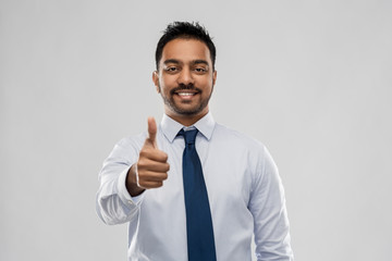 Wall Mural - business, office worker and people concept - smiling indian businessman in shirt with tie showing thumbs up over grey background