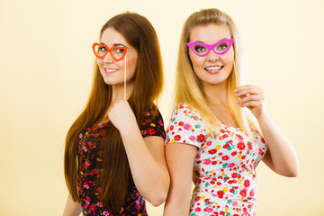 Poster - Two happy women holding fake eyeglasses on stick