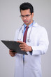 © Ranta Images - Portrait of young handsome Indian man doctor reading on clipboard
