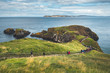 Tourists walking on the wooden path to the ocean. Northern Ireland. People hiking among the grass covered cliff to the Irish shoreline. Picturesque landscape. Ideal place for the outdoor activity.
