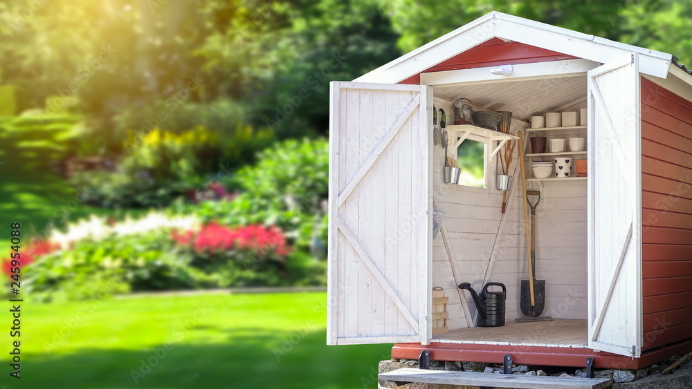Storage shed filled with gardening tools. Beautiful green botanical garden in the background. Copy space for text and product display. - obrazy, fototapety, plakaty 