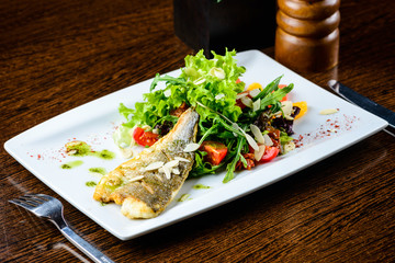 Canvas Print - Appetizing tasty baked fish served with tomatoes, oranges and spices in the white plate