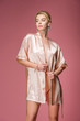 © LIGHTFIELD STUDIOS - attractive young woman posing in silk robe, isolated on pink