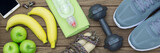 Fototapeta  - Top view of Healthy lifestyle concept, sport equipments and fresh foods on wood background.  Web Banner.