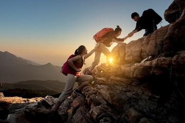 group of asia hiking help each other silhouette in mountains with sunlight..
