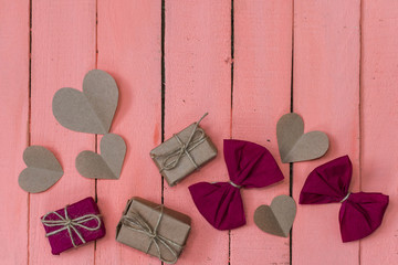 gifts, bows and hearts on pink wooden background