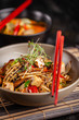 © zukamilov - The concept of Japanese cuisine. Chinese noodles with chicken, grilled vegetables, and tofu in unagi sauce. Serving Asian dishes in the restaurant in a plate on a bamboo mat. Top view, copy space
