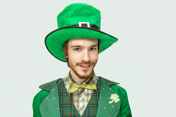 Young redhead man in green saint Patrick's costume and hat look straight on camera. Isolated on white background.