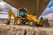 Backhoe in construction tasks of a road. Preparation of the land for the construction of a bridge on the highway