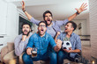 Men watching sport on tv together at home screaming cheerful. Group of friends sitting on the couch and watching a football game.