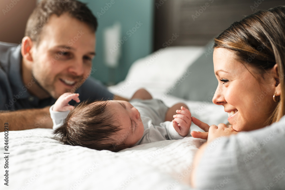 A beautiful couple with newborn Baby on bed. - obrazy, fototapety, plakaty 