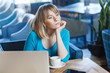 © khosrork - Beautiful thinkful young girl freelancer with blonde bob haircut hair in blue blouse are sitting in cafe and dreaming, having new idea and planning own strategy, holding one hand on chin.