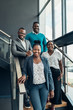 © JonoErasmus - Team of african business people smiling and standing on stairs in a modern office
