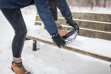 Woman Putting Non Slip Snow Cleat On Hiking Boot In Winter