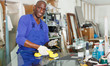 smiling African American glazier choosing glass for cutting in workshop