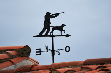 a metal vane with a hunter ans a dog in a dark cloudy sky