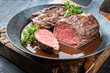 Traditional barbecue aged saddle of venison with herbs game sauce as closeup in a wrought iron skillet