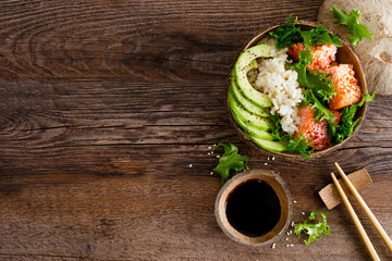 Hawaiian poke coconut bowl with grilled salmon fish, rice and avocado. Healthy food. Top view