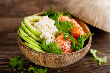 Hawaiian poke coconut bowl with grilled salmon fish, rice and avocado. Healthy food