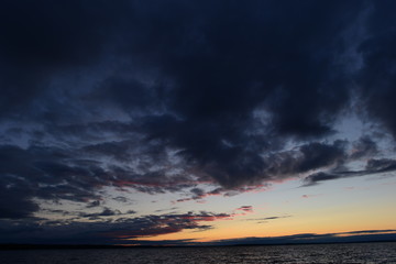 Wall Mural - Dark clouds of the twilight sky over the water surface of the lake