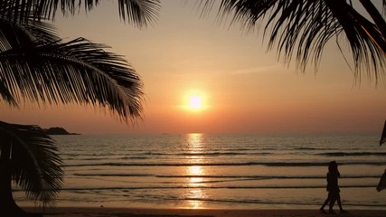 Wall Mural - Silhouette of a couple walking on a tropical beach at sunset on a tropical island in Thailand