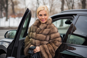 Luxurious lady in fur coat with auto. Woman around car at city, automobile concept 