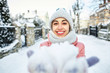 © vitaliymateha - happy joyful smiling woman in warm winter clothes holding a snow in a both palms and shows it at the camera.