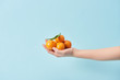 © LIGHTFIELD STUDIOS - cropped view of woman holding organic tangerines in hand isolated on blue