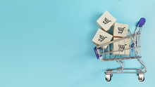 Boxes In A Shopping Cart On Blue Background. Concept: Online Shopping, E Commerce And Delivery Of Goods. Copy Space.