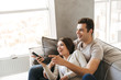 © Drobot Dean - Happy young couple sitting on a couch at home