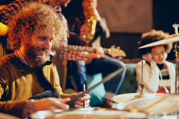 Wall Mural - Caucasian drummer playing his instrument while sitting in home studio.