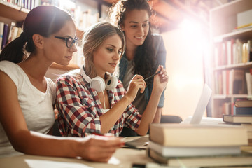 Wall Mural - In the tranquil morning hours, a diligent group of female students assembles in the college library, gearing up for a productive day of focused studying and preparation.