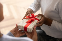 Close Up Of African American Child Present Birthday Gift To Mom Or Nanny, Black Excited Teenage Girl Make Surprise For Mother, Congratulating Her On Special Occasion, Having Close Moment Together