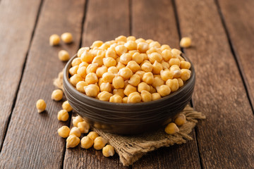 Chickpeas in ceramic bowl on dark wooden rustic table. Selective focus.