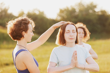 Mother and two young daughters do yoga oh in the park on a sunny summer day. Concept of health and longevity at any age