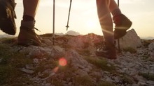 SLOW MOTION CLOSE UP SUN FLARE: Active Man And Woman In Hiking Boots Walk Up To The Mountain Peak On A Picturesque Summer Evening In The Alps. Young Couple Exploring The Beautiful Mountains At Sunset.