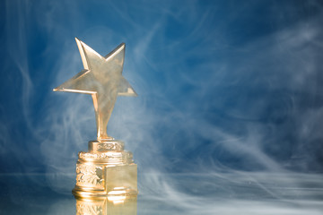 Wall Mural - gold star trophy in smoke, blue background