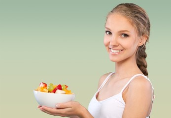 Wall Mural - Young woman eating delicious food with fork on green background