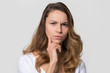 Puzzled perplexed young woman with distrustful face isolated on blank studio wall, unbelieving suspicious girl looking at camera doubtful uncertain bewildered criticize on white background portrait
