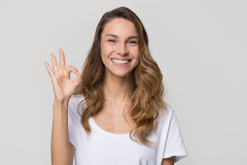 Wall Mural - Happy woman gesturing ok smiling with white teeth looking at camera isolated on studio blank background, pretty girl hand showing okay sign satisfied with dental orthodontic service concept, portrait