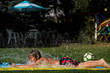 © Kirsten Lewis - Side view of shirtless boy playing on water slide